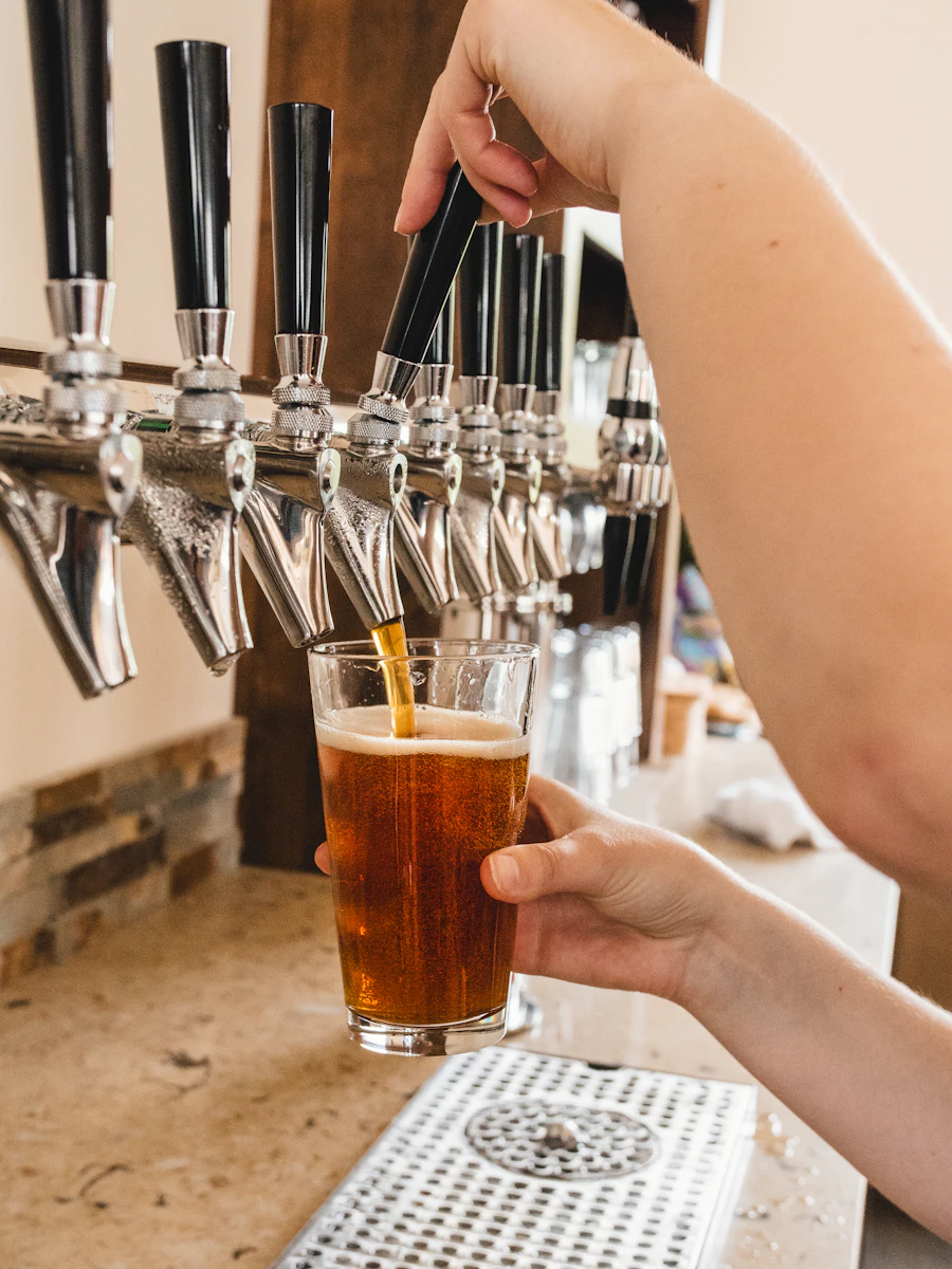 A hand holding a glass of amber beer