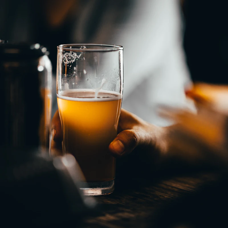 A glass of golden beer in low light