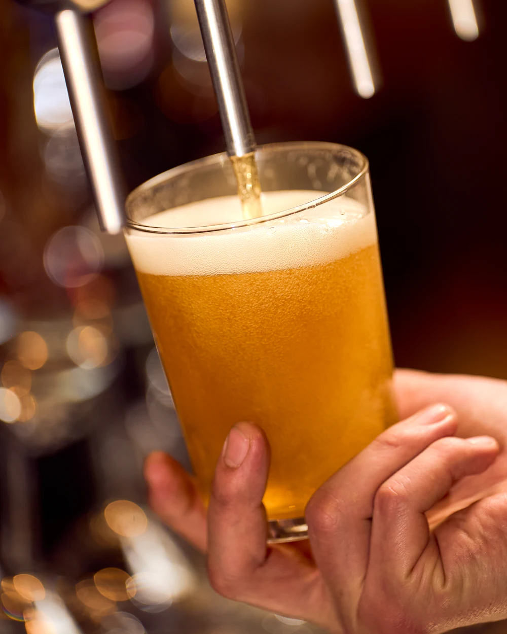 Golden beer being poured into a glass from a tap